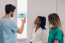 Group of doctors looking at x-ray image from jaw while working in a hospital. Multiracial oral surgeons. Healthcare, medical and radiology concept.
