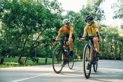Smiling sporty couple on bicycles during weekend cycle ride while wearing sports clothes and helmets. Traveling by high-performance sport bicycles. Sports and healthy lifestyle. Copy space.