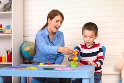 Toddler boy in child occupational therapy session doing sensory playful exercises with her therapist.