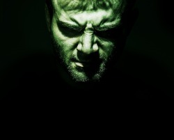 Low key portrait of evil, devil, bad, angry face of man on a black background, dark side human soul, crazy