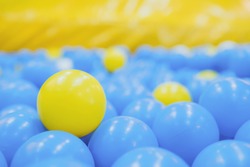 Close up of plastic yellow and blue balls at the playground. Soft focus. Background.