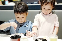 Cute asian boy and girl eating rice by self. Copy space. Learning Concept.