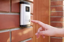The female hand presses a button doorbell with camera and intercom