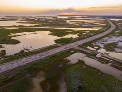 Aerial drone view of a swamp at amazing bright sunset. Aspalt Road through the Lakes and Marsh