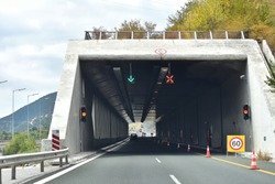 Road tunnel in mountains. Mountain road tunnel with luminous safety lights and yellow road line. Tunnel on the highway.  Automobile trip. Pathway with tunnel. Drive through the mountain