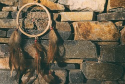 Dreamcatcher – Native American culture willow hoop. Dream catcher on stone wall background – stone texture. Traditional shamanist equipment. Concept of mystic, magic or the healing power of nature.