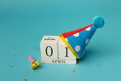 April 1st. Image of april 1 wooden calendar and festive decor on the blue background. April Fool's Day.