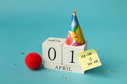 April 1st. Image of april 1 wooden calendar and festive decor on the blue background. April Fool's Day.