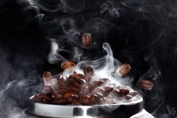 
Hot grain macro shot. Coffee beans on a black background. Roasted coffee beans with smoke.
