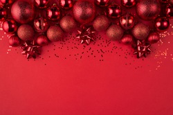 Christmas celebration concept. Top above overhead view close up photo of beautifully decorated red baubles and confetti isolated on red background with copyspace