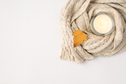 Top view photo of lighted candle in candlestick sweater and orange autumn leaf on isolated white background with copyspace