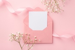Wedding invitation concept. Top view photo of open pink envelope with paper card pink curly ribbon and white gypsophila flowers on isolated pastel pink background with empty space