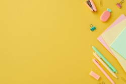 Back to school concept. Top view photo of colorful school accessories notepads pineapple shaped eraser stapler binder clips and pens on isolated yellow background with empty space