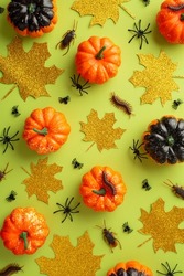 Halloween concept. Top view vertical photo of pumpkins gold sparkle leaves spiders centipedes and cockroaches on isolated light green background
