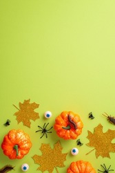 Halloween concept. Top view vertical photo of pumpkins gold sparkle leaves eyeballs spiders centipedes and cockroaches on isolated light green background with copyspace