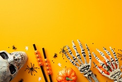 Halloween party accessories concept. Top view photo of skull skeleton hands pumpkins spiders straws and confetti on isolated orange background with copyspace