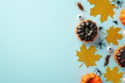 Halloween spooky decorations concept. Top view photo of pumpkins gold glitter maple leaves eyes spiders cockroach and centipede on isolated pastel blue background with empty space