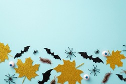 Halloween concept. Top view photo of gold sparkle maple leaves bat silhouettes eyes spiders cockroach and centipedes on isolated pastel blue background with copyspace