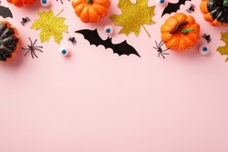 Halloween creepy decorations concept. Top view photo of pumpkins gold sparkle leaves eyes insects spiders and centipede on isolated pastel pink background with empty space