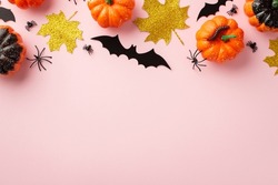 Halloween spooky decorations concept. Top view photo of pumpkins gold glitter leaves spiders and centipede on isolated pastel pink background with empty space