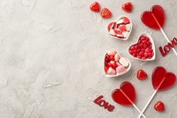 Valentine's Day concept. Top view photo of heart shaped lollipops plates with candies and inscriptions love on concrete texture background with copyspace