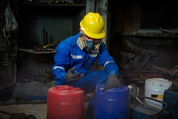A Worker industry wearing safety uniform ,black gloves and gas mask under checking chemical tank in industry factory work