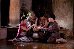 Asia Couple pour water on the hands of revered elders, grand parent doing for respected and ask for blessing in Songkran festival famous Thai cultural on April day is family concept.