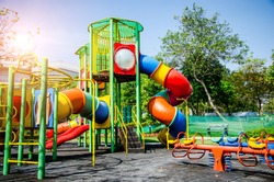 Colorful children playground,exercise kid,activities in outdoor public park surrounded by green trees at sunlight morning.Children run, slide,seesaw on modern playground.Funny toy land for child