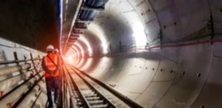 Blurred background of underground tunnel construction with light at the end of the tunnel.Transport pipeline by Tunnel Boring Machine for electric train subway with control engineer or security safety