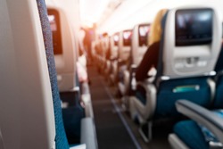 Soft focus and blurred background of passengers on commercial aircraft ,airplane or plane that  airplane cabin interior with seats,air transport is the current popular and fast with lighting.