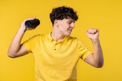 Man dancing, enjoying on yellow studio background. Guy moves to rhythm of music. Young teenager listening to music by wireless portable speaker - modern sound system. . High quality photo