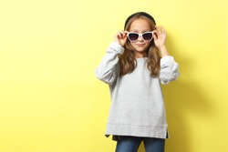 Little cheerful smiling girl in fashionable clothes on a colored background. Children's clothing, children's fashion
