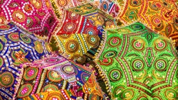 A colorful set of parasols with vibrant colors and intricate patterns, for sale as tourist souvenirs on a street in Jaipur, India.