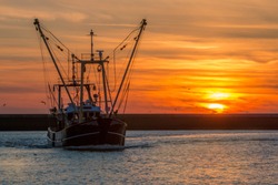 Fishers boat entering the habor of Harlingen during sunset