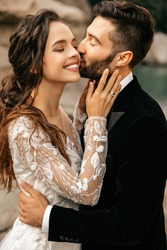 Beautiful wedding couple laugh and kiss on the background of stones. High quality photo