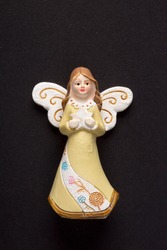 Ceramic ornament angel figurine isolated on black background. Beliefs, religious icons and symbols concepts. Vertical close-up.
