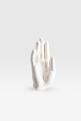 abstract sculpture in shape of human arm in white paint on white surface