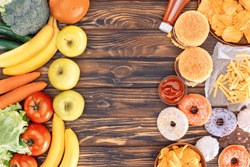 top view of fresh ripe fruits with vegetables and assorted junk food on wooden table