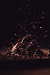  closeup view of grated dark chocolate falling on pieces of chocolate on black background 