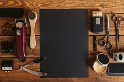 top view of professional barber tools and blank black card on wooden table 