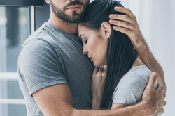 cropped shot of bearded man hugging and supporting young sad woman