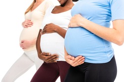 cropped view of three pregnant women holding hands on bellies isolated on white