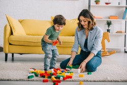 Mother and son playing with lego on carpet in living room