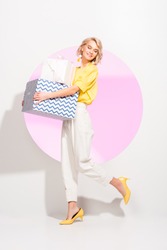 beautiful fashionable girl holding gift boxes and smiling on white with pink circle