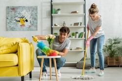happy man and woman doing spring cleaning in apartment