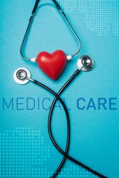 Top view of decorative red heart with black stethoscope on blue background, medical care illustration