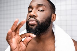 portrait of afro-american man using cure for strengthening beard growth
