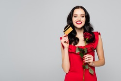 happy woman holding red rose and credit card isolated on grey