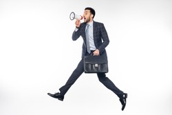 businessman in suit jumping with briefcase and screaming in loudspeaker on white