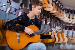 Side view of customer playing acoustic guitar in instrumental music shop